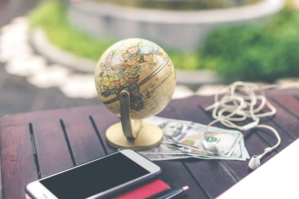 image of globe, smartphone, earbuds, pen and money. extra money making ideas. 