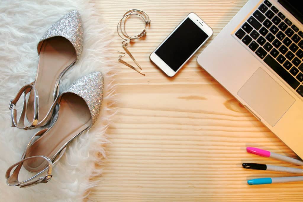 glitter flats on a rug, earrings, and permanent markers next to a cell phone and laptop 