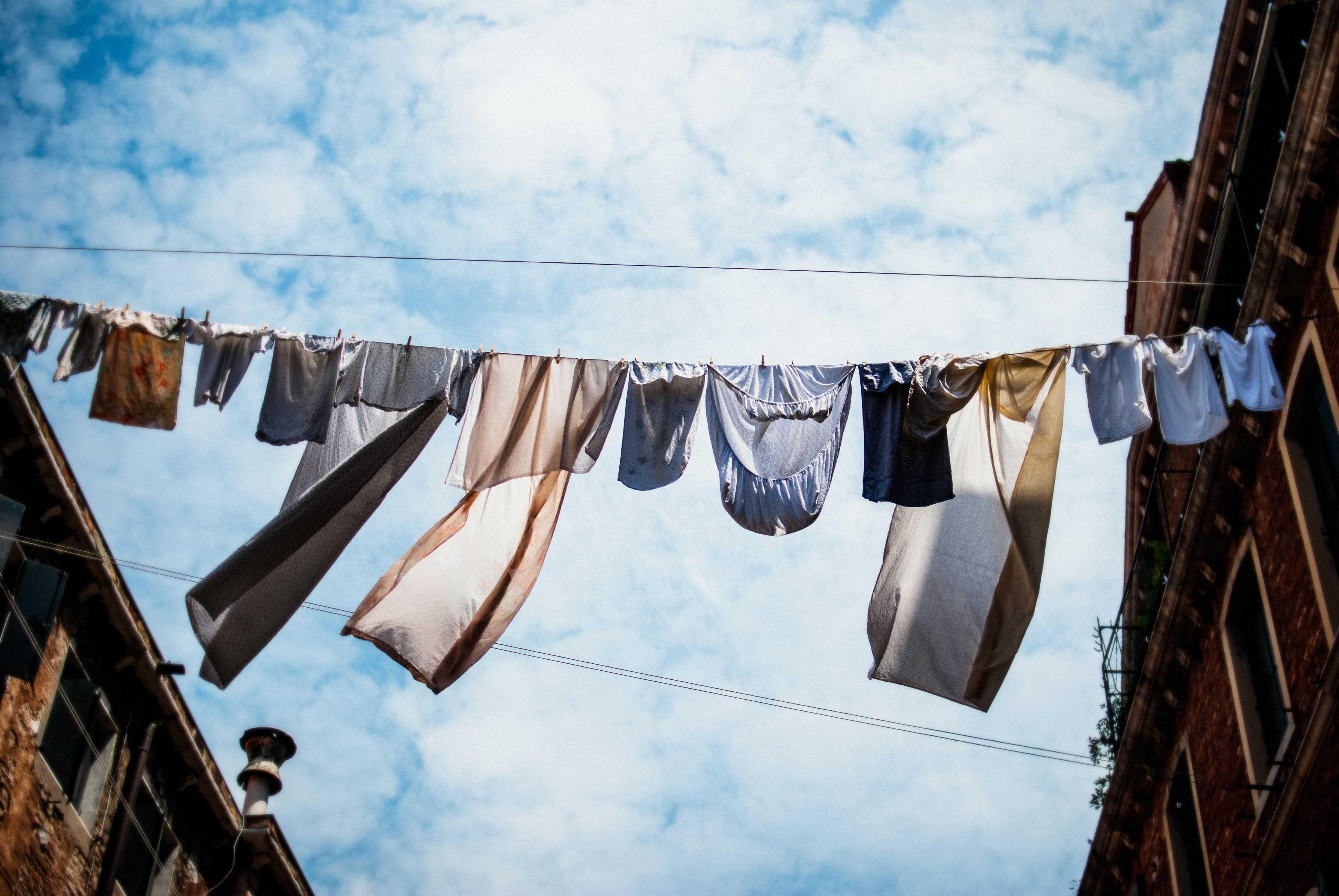 frugal living tips for laundry. Photo of laundry hanging out to dry from a building. 