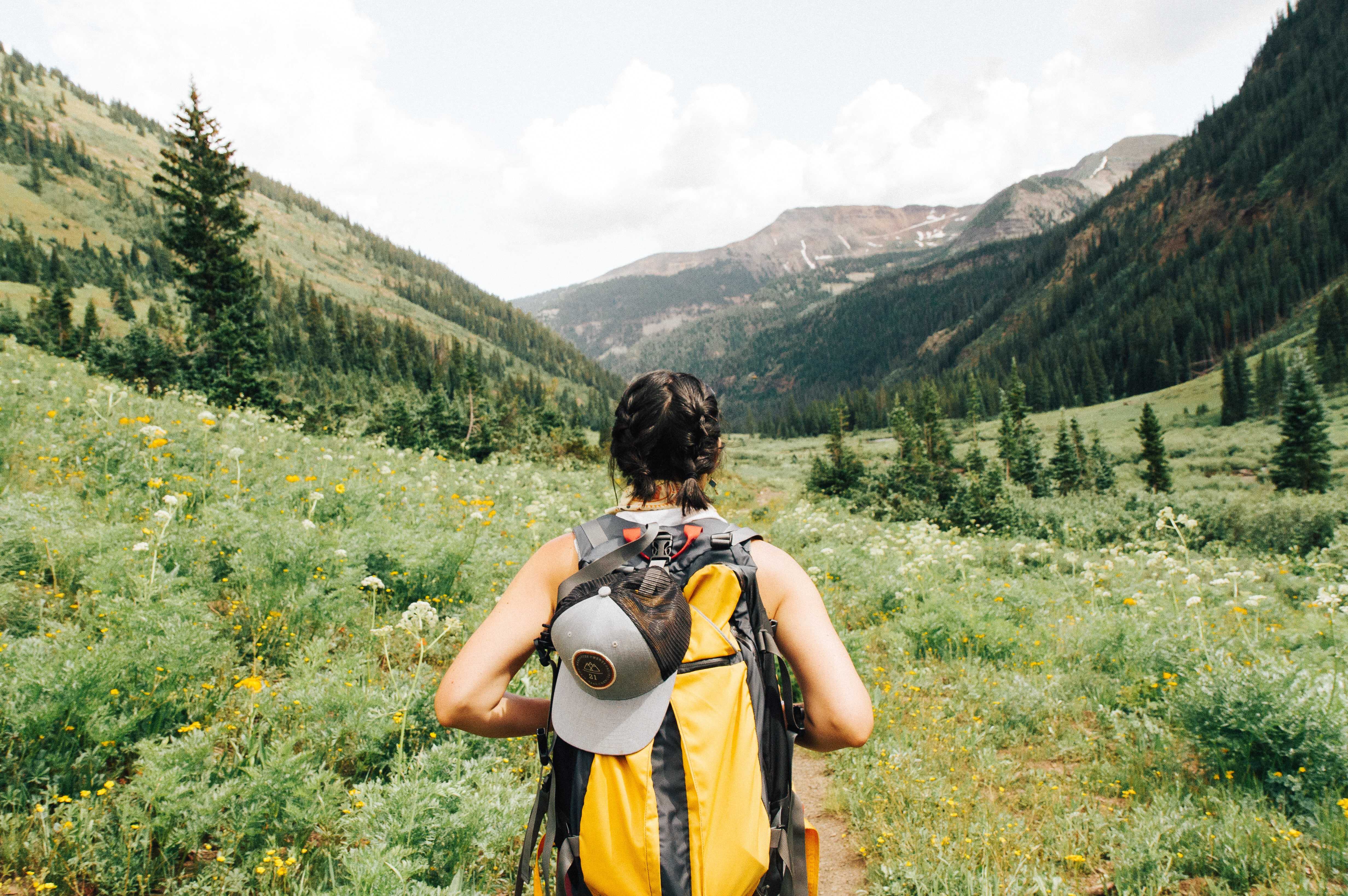 frugal living tips for outside activities. Picture of woman looking out at mountains while on a trail