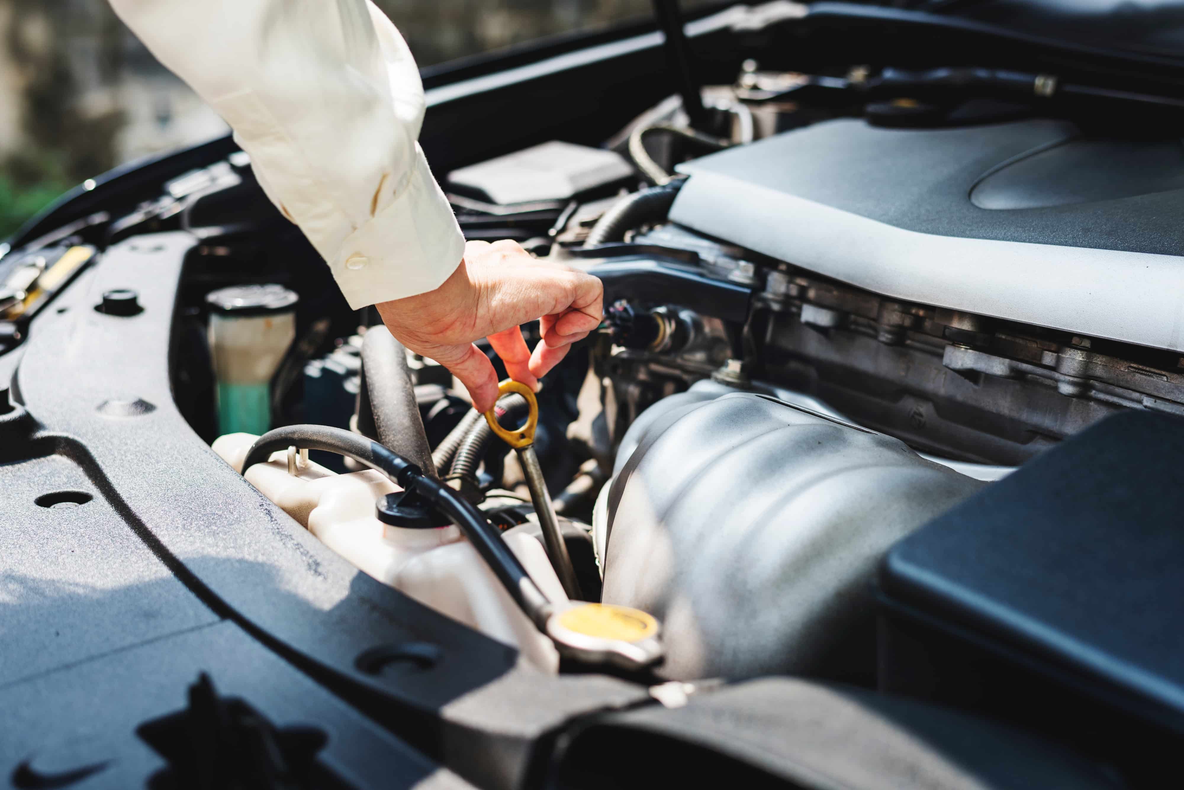 Person checking their oil levels in their car and performing other auto services image.