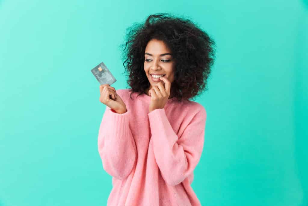 Women holding travel hacking rewards credit cards with a greenish blue background.