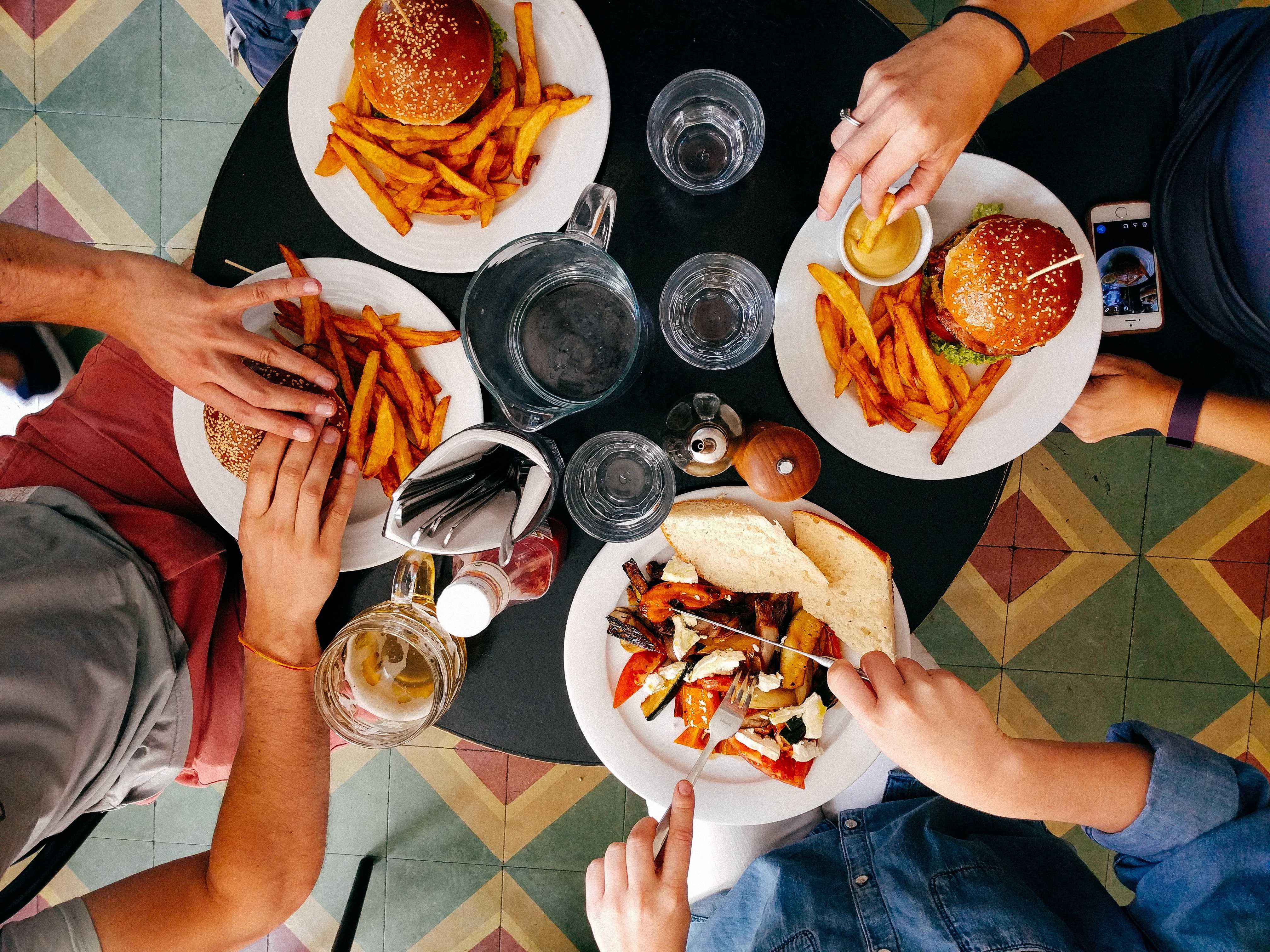 Picture of friends out to lunch with sandwiches and French fries on their plates. 