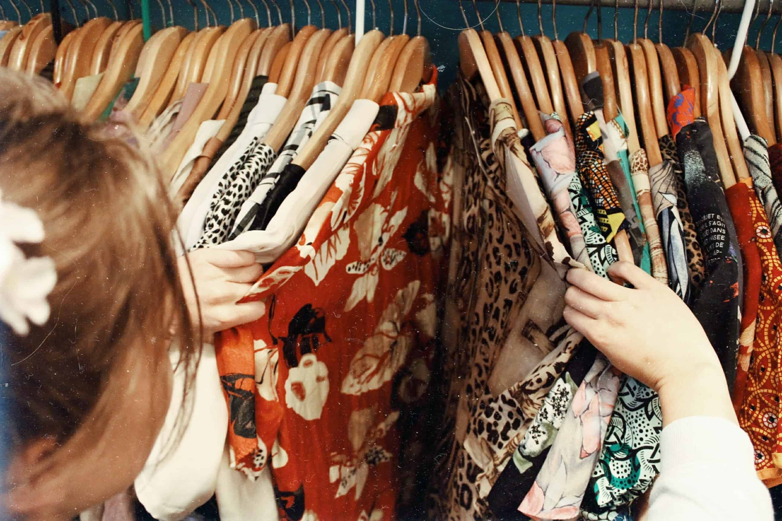 thrift store flipping clothes. Image of women going through her clothes within her closet.