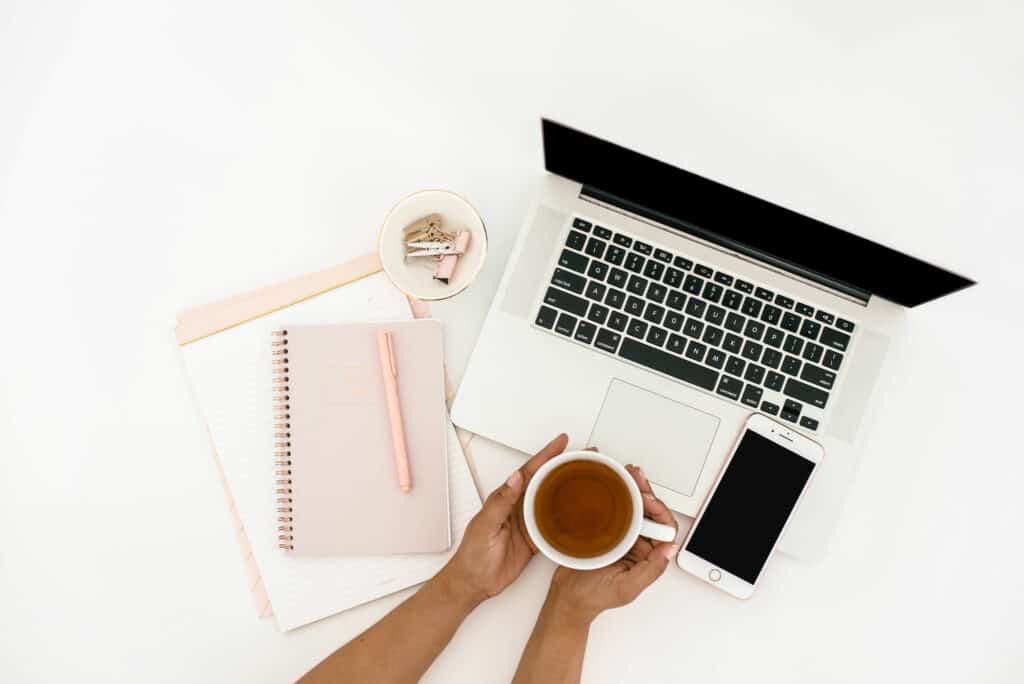 best work from home jobs accountant image of woman with her laptop, cell phone, journal, pen and cup of tea in hand.