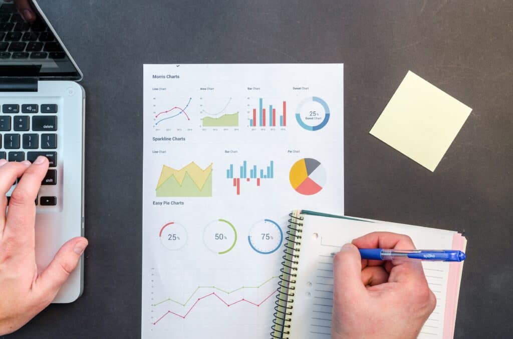 best work from home jobs data analyst image of man working on laptop alongside a notebook and a graph chart. 